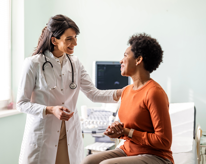 Woman in orange shirt being comforted by female healthcare provider