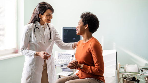 Woman in orange shirt being comforted by female healthcare provider